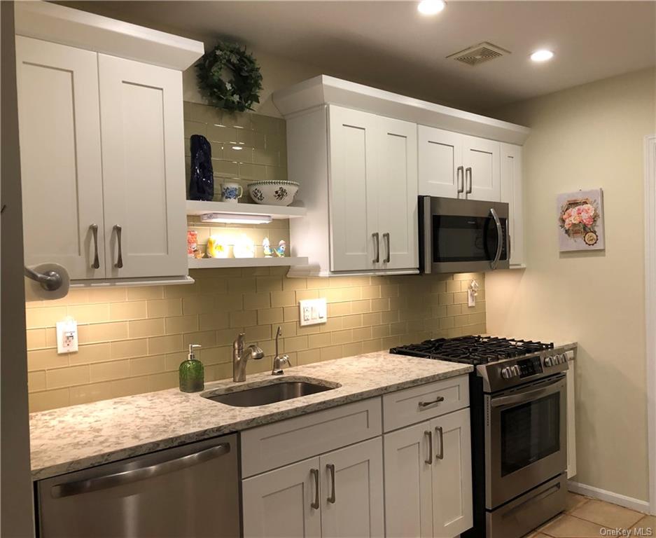 a kitchen with stainless steel appliances granite countertop a sink dishwasher a stove and a microwave oven with cabinets