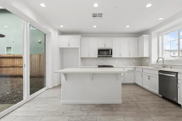 a kitchen with stainless steel appliances granite countertop a stove a sink and a refrigerator