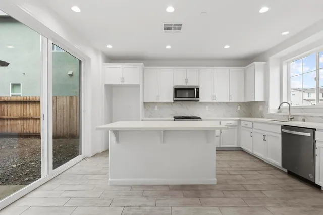 a kitchen with stainless steel appliances granite countertop a stove a sink and a refrigerator