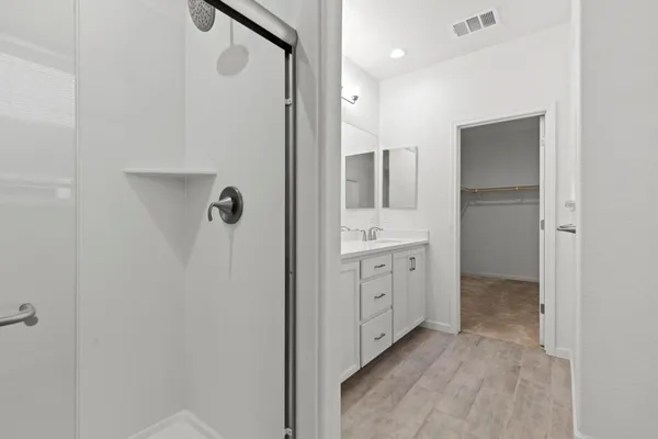 a spacious bathroom with a double vanity sink a large mirror and shower