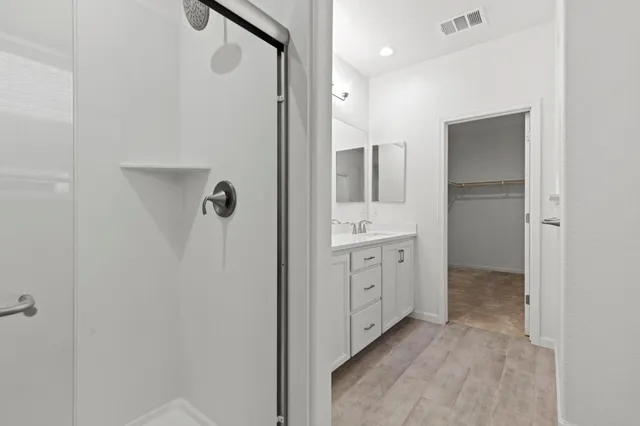 a spacious bathroom with a double vanity sink a large mirror and shower