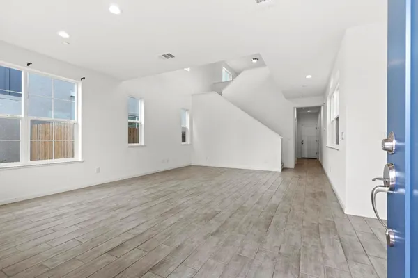 an empty room with wooden floor and windows