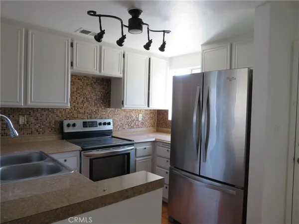 a kitchen with stainless steel appliances granite countertop a refrigerator a sink a stove and white cabinets