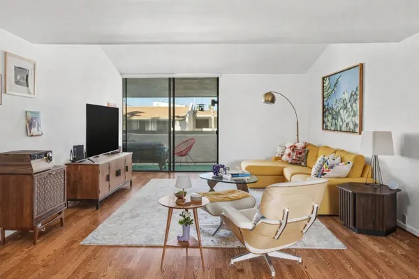 a living room with furniture a flat screen tv and a floor to ceiling window
