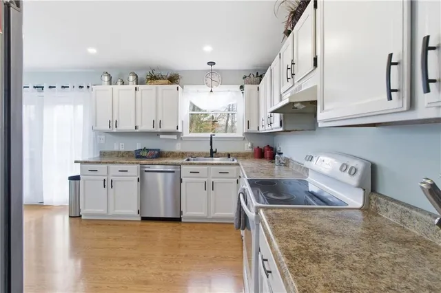 a kitchen with stainless steel appliances granite countertop a sink a stove and a refrigerator