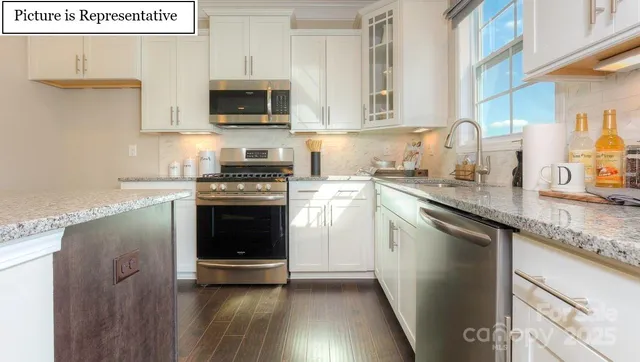 a kitchen with granite countertop a stove top oven a sink and dishwasher with wooden floor