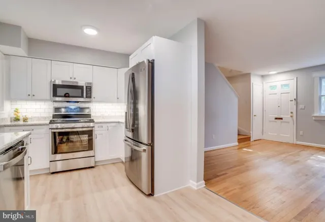 a kitchen with granite countertop a refrigerator and a stove top oven