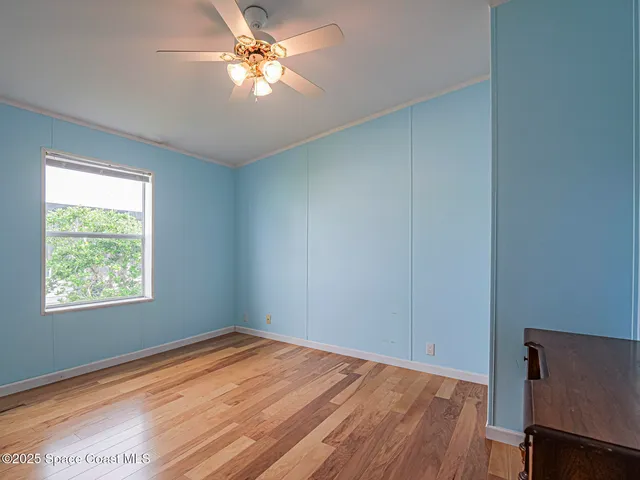 a view of empty room with wooden floor and fan
