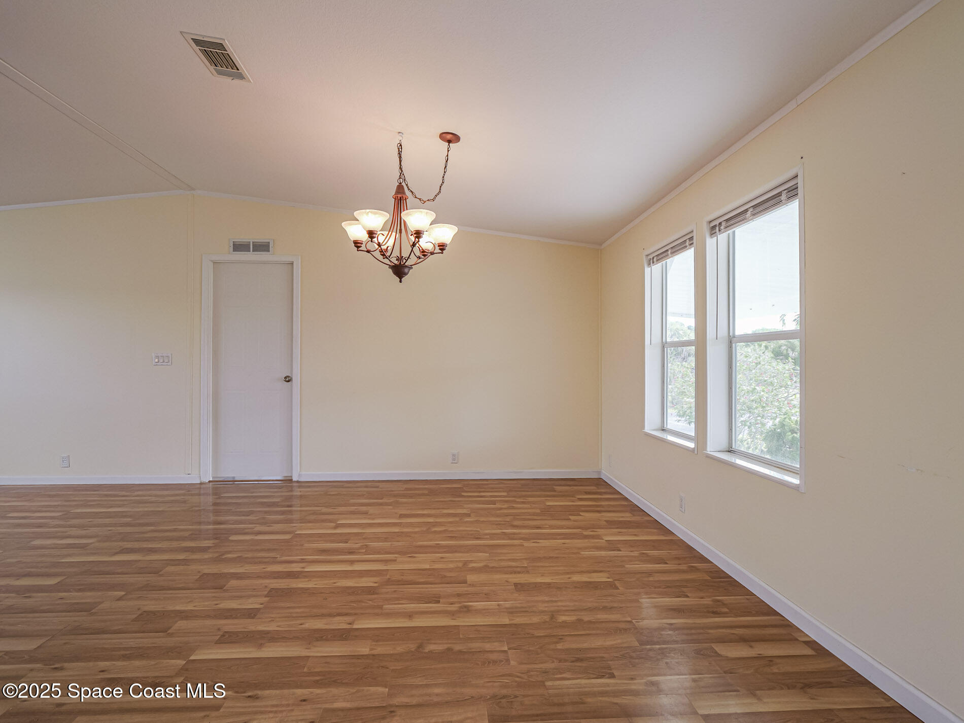 7620 Boxelder Road Micco, FL 32976 - Photo 9 of 47 a view of an empty room with chandelier and wooden floor