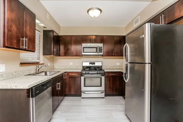 a kitchen with stainless steel appliances granite countertop a refrigerator a stove a sink and a microwave