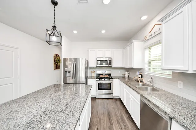 a kitchen with stainless steel appliances granite countertop a sink refrigerator and cabinets