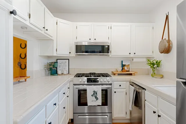 a kitchen with stainless steel appliances white cabinets and a stove a oven with white countertops