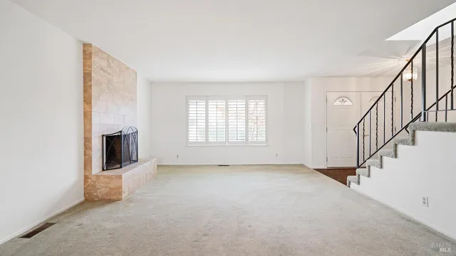 a view of an empty room with a fireplace and a window