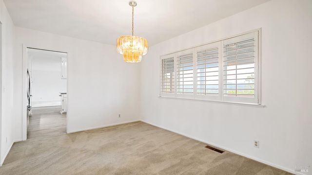 a view of an empty room with a window and chandelier