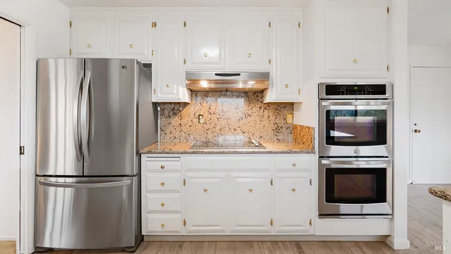 a kitchen with stainless steel appliances a refrigerator stove and white cabinets