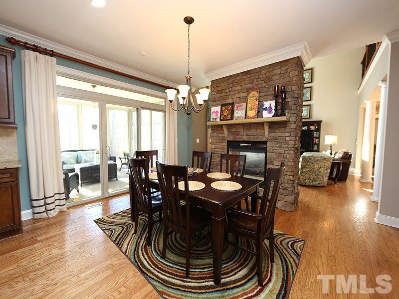 12913 Baybriar Drive Raleigh, NC 27613 - Photo 11 of 25 a dining room with furniture wooden floor a rug a fireplace and a chandelier