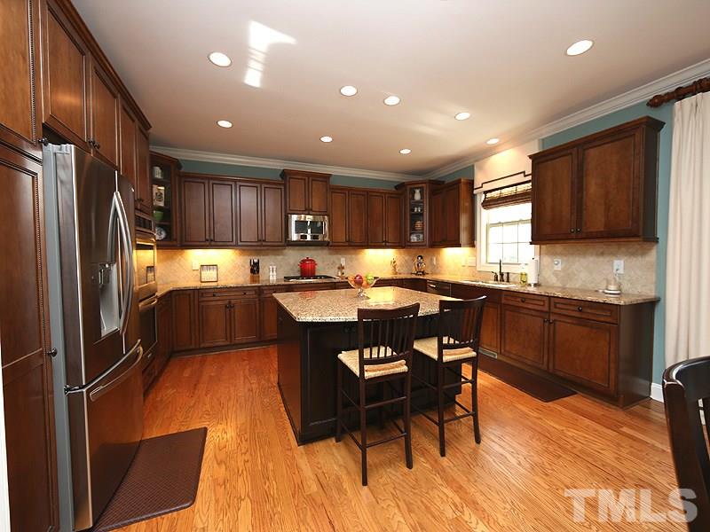 12913 Baybriar Drive Raleigh, NC 27613 - Photo 9 of 25 a kitchen with stainless steel appliances granite countertop a refrigerator sink and wooden cabinets