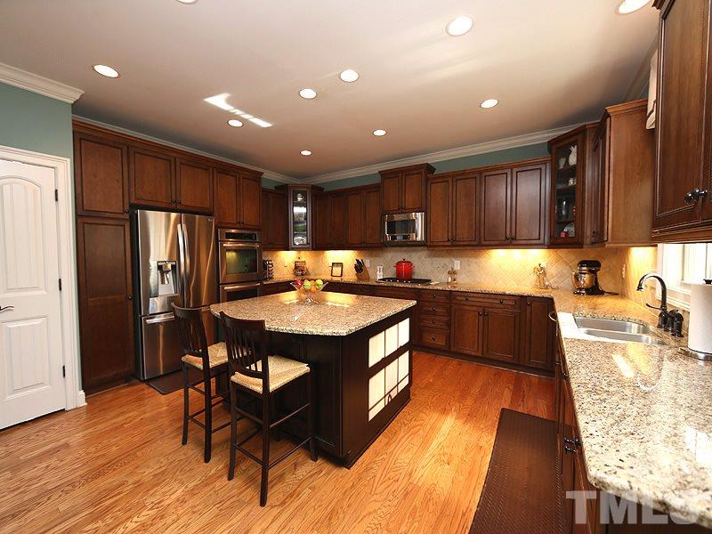 12913 Baybriar Drive Raleigh, NC 27613 - Photo 10 of 25 a kitchen with kitchen island granite countertop wooden floors wooden cabinets a center island and stainless steel appliances
