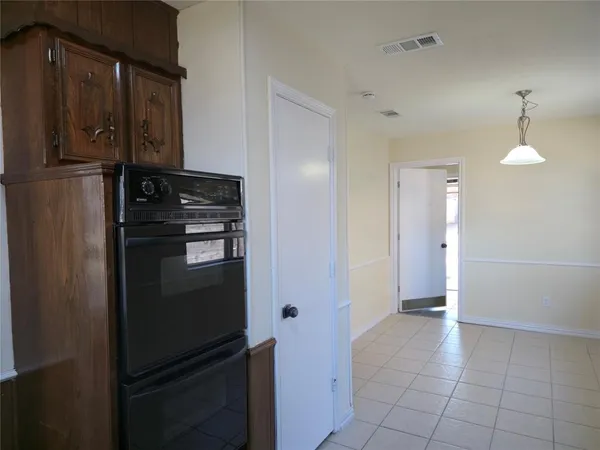a view of a refrigerator in kitchen and an empty room in wooden