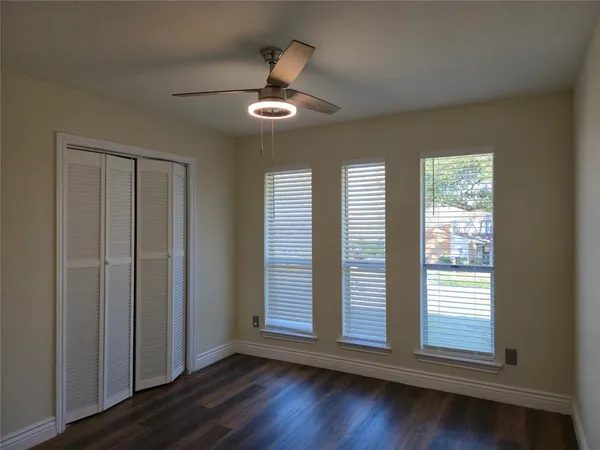 an empty room with wooden floor chandelier and windows