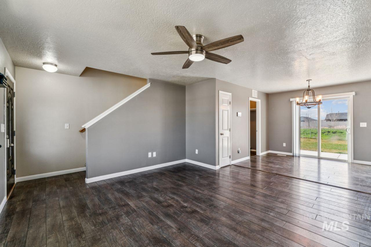 5410 Barkley Way Caldwell, ID 83607 - Photo 13 of 50 Unfurnished living room featuring dark wood-style flooring, a ceiling fan, suspended lighting, and a textured ceiling