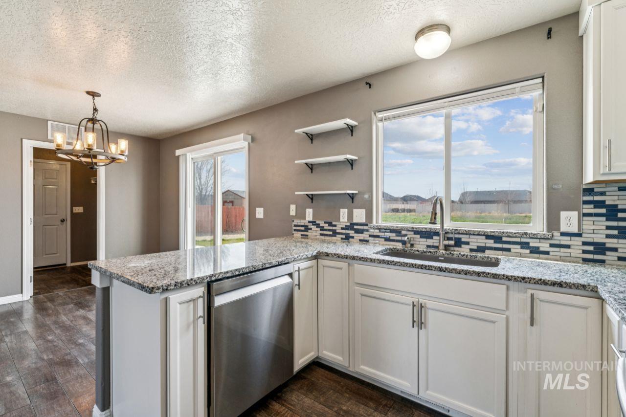 5410 Barkley Way Caldwell, ID 83607 - Photo 17 of 50 Kitchen featuring open shelves, a peninsula, dark wood finished floors, decorative backsplash, and dishwasher