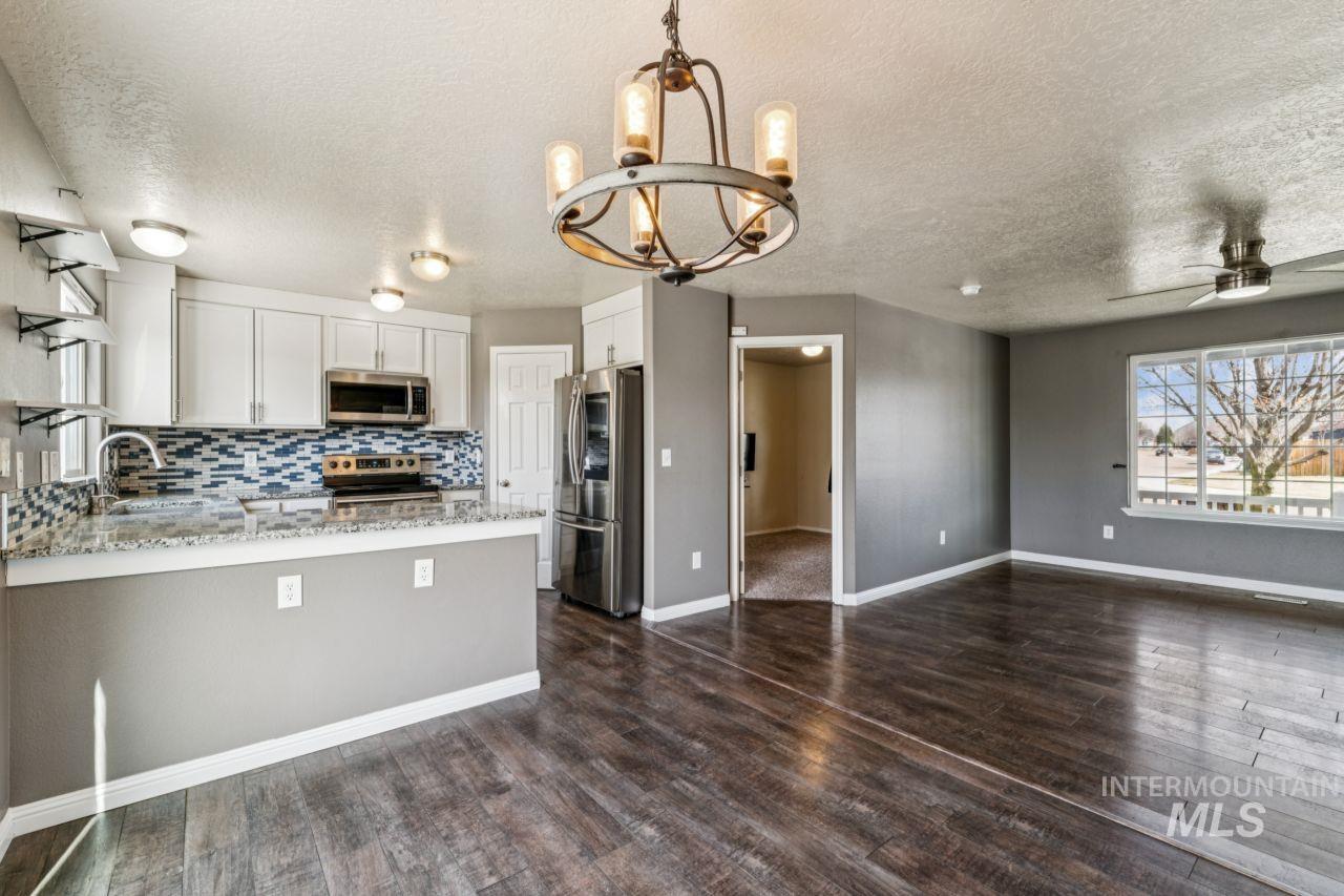 5410 Barkley Way Caldwell, ID 83607 - Photo 19 of 50 Kitchen with plenty of natural light, light stone countertops, stainless steel appliances, white cabinets, and a textured ceiling