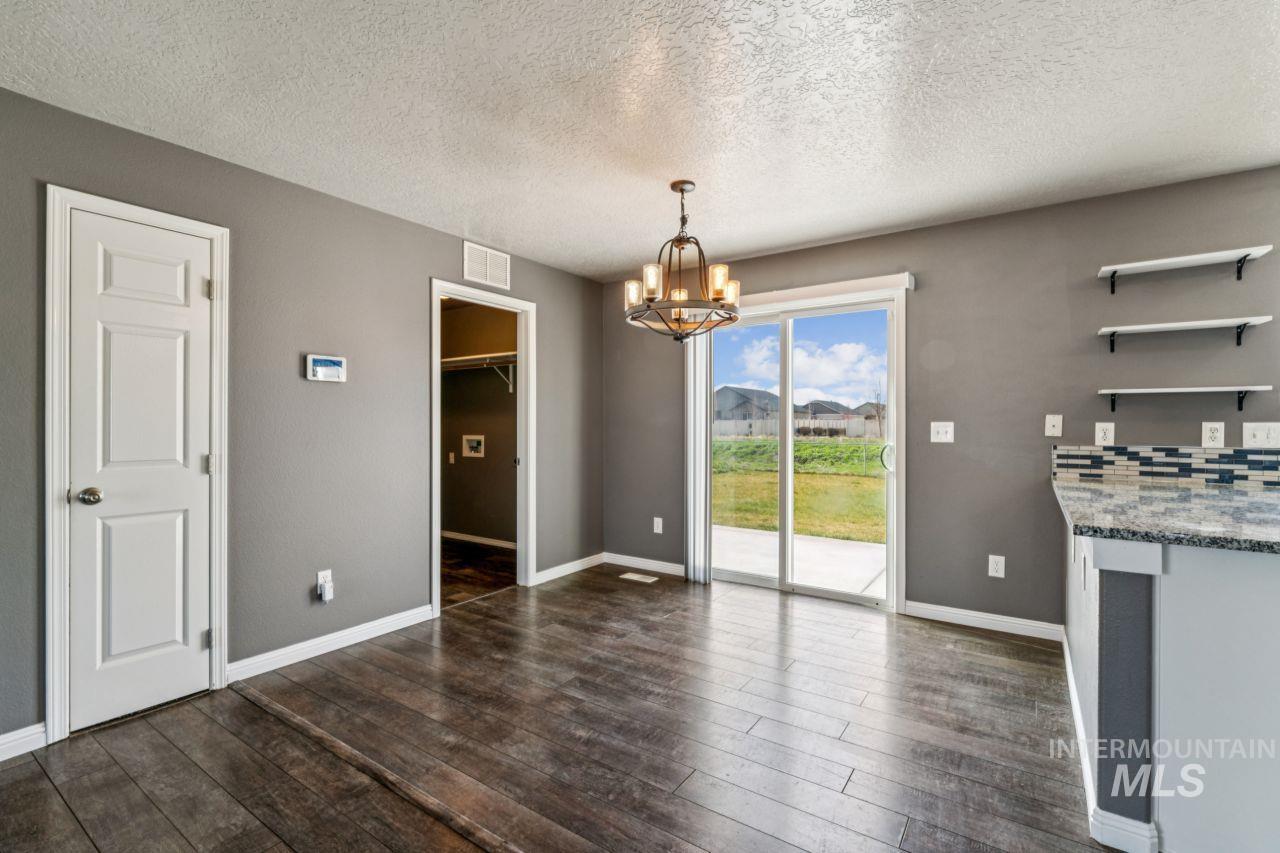 5410 Barkley Way Caldwell, ID 83607 - Photo 36 of 50 Unfurnished dining area featuring dark wood finished floors, a chandelier, and a textured ceiling