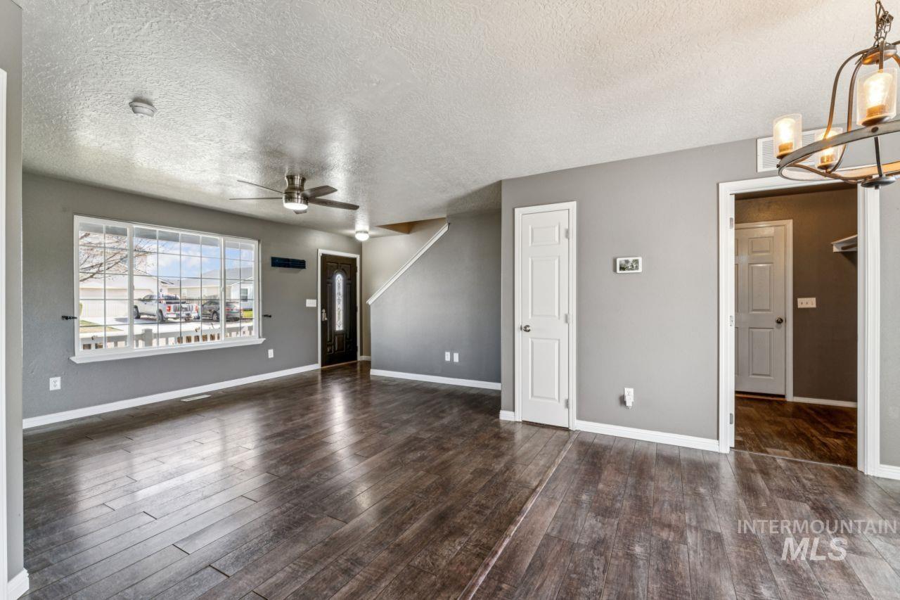 5410 Barkley Way Caldwell, ID 83607 - Photo 10 of 50 Unfurnished living room featuring a textured ceiling, ceiling fan, dark wood-style floors, and a chandelier