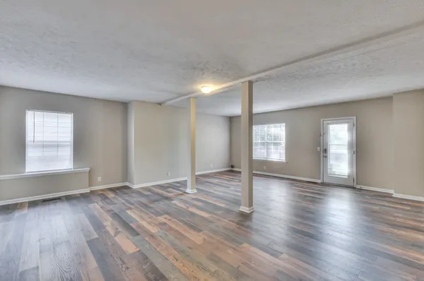 an empty room with wooden floor and windows