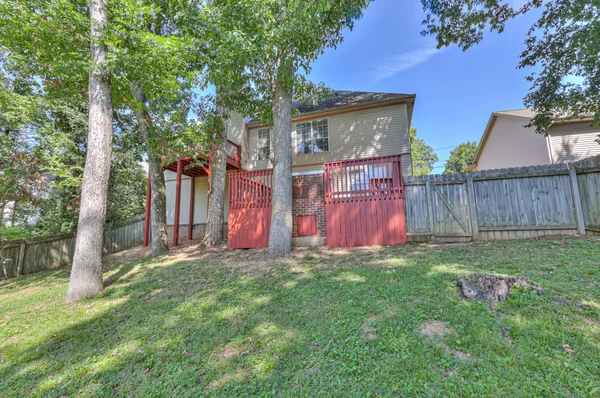 a view of a backyard with large trees and wooden fence
