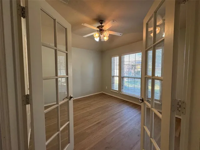 a view of an empty room with wooden floor and a window