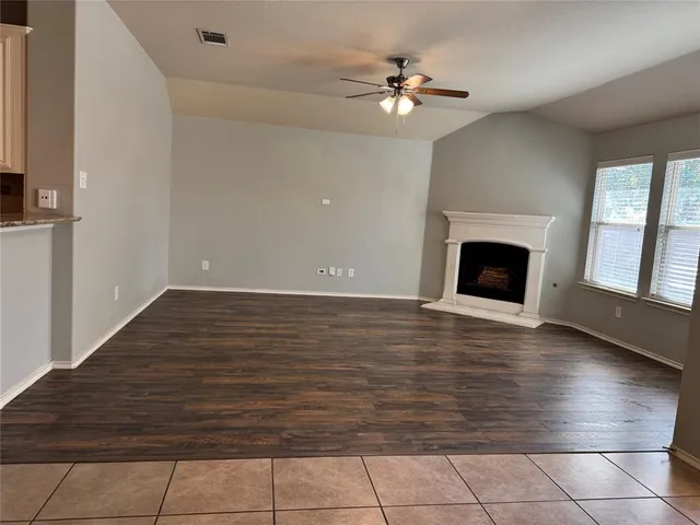 a view of an empty room with wooden floor and fireplace