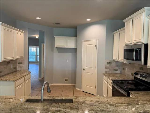 a kitchen with stainless steel appliances granite countertop a stove top oven a sink and a refrigerator