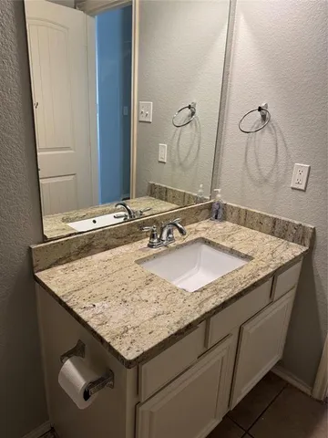 a bathroom with a granite countertop sink and a mirror