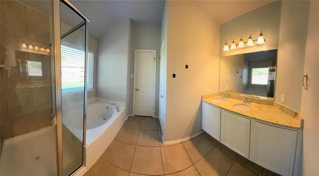 a bathroom with a granite countertop sink a mirror and a bathtub