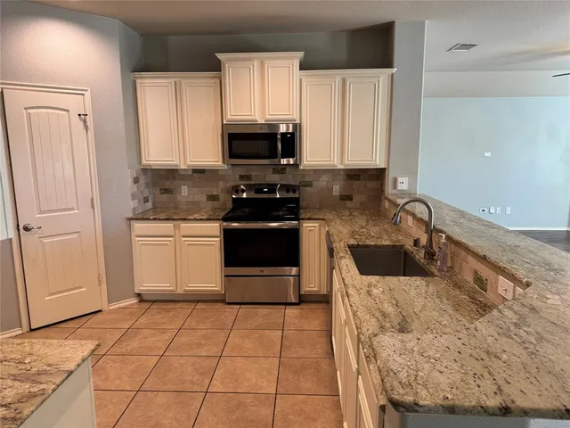 a kitchen with stainless steel appliances granite countertop a stove a sink and a microwave