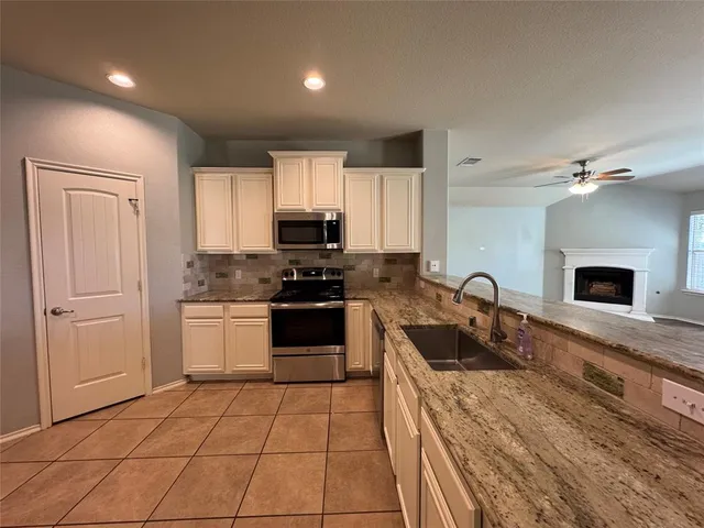 a large kitchen with a stove a sink a microwave and cabinets