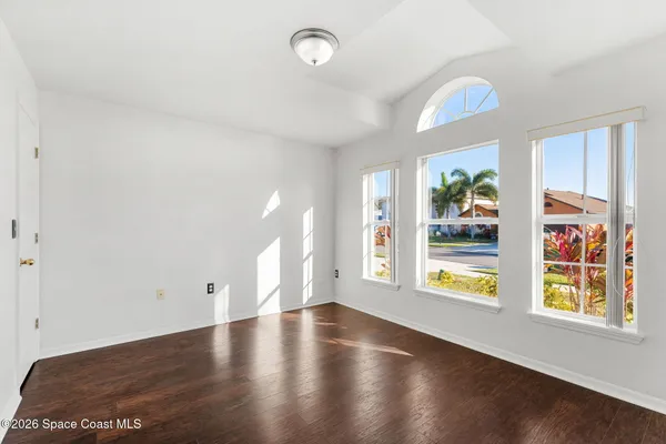 an empty room with wooden floor and ceiling fan