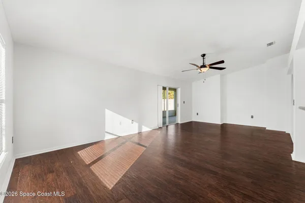 a view of empty room with wooden floor and fan