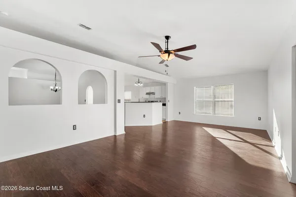 an empty room with wooden floor a ceiling fan and windows