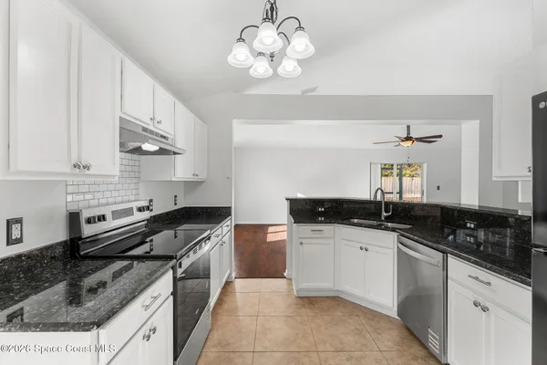 a kitchen with stainless steel appliances granite countertop a sink a stove a refrigerator cabinets a dining table and chairs