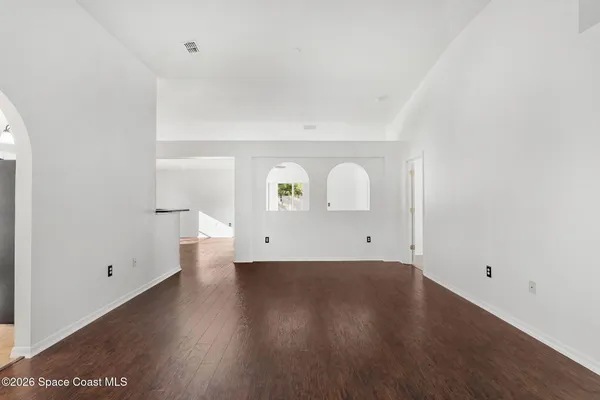 an empty room with wooden floor and ceiling fan
