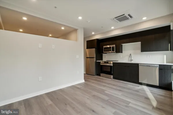 a large kitchen with a large counter top stainless steel appliances and cabinets