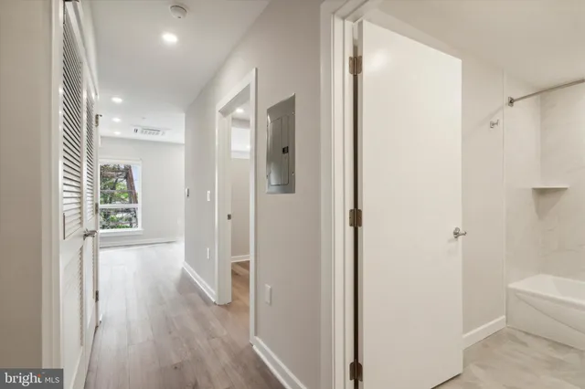 a view of a hallway with wooden floor and a bathroom