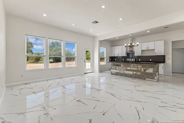 a large kitchen with stainless steel appliances kitchen island granite countertop a large counter top and a stove top oven