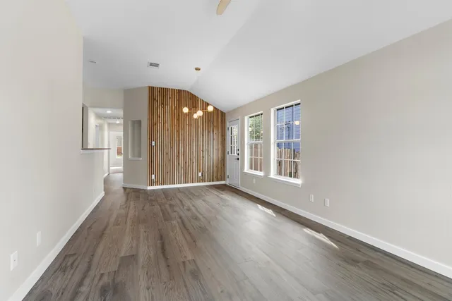 a view of an empty room with wooden floor and a window