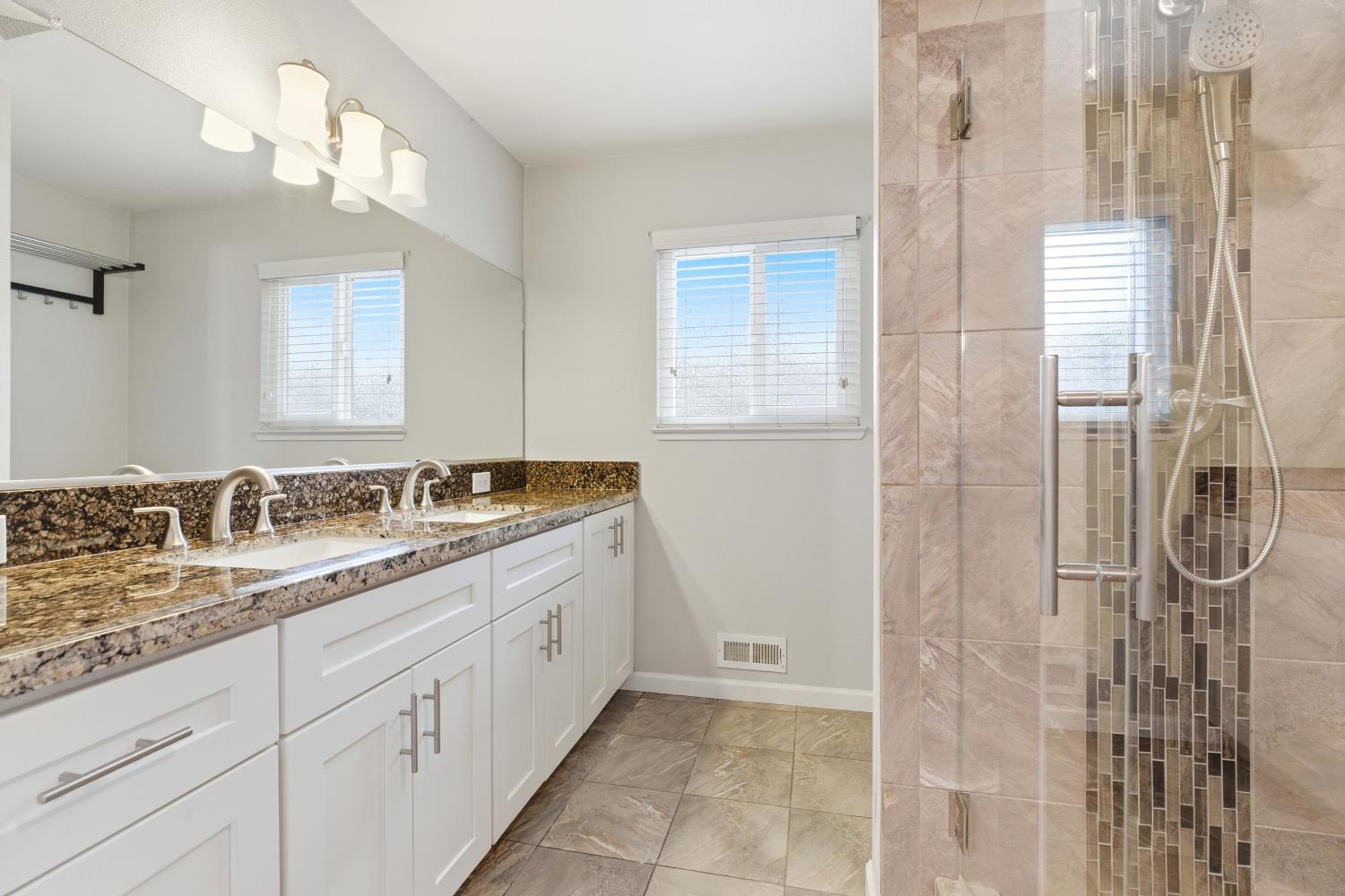 1416 Buttonwillow Drive Modesto, CA 95355 - Photo 24 of 39 a bathroom with a granite countertop sink a mirror and a shower