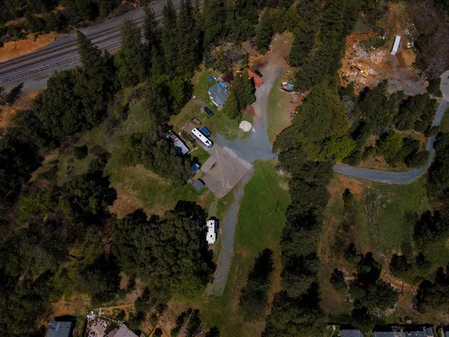 an aerial view of residential house with outdoor space and trees all around