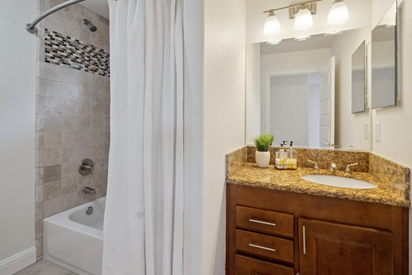 24475 Mountain Charlie Road Los Gatos, CA 95033 - Photo 15 of 69 a bathroom with a granite countertop sink a mirror a vanity and bathtub